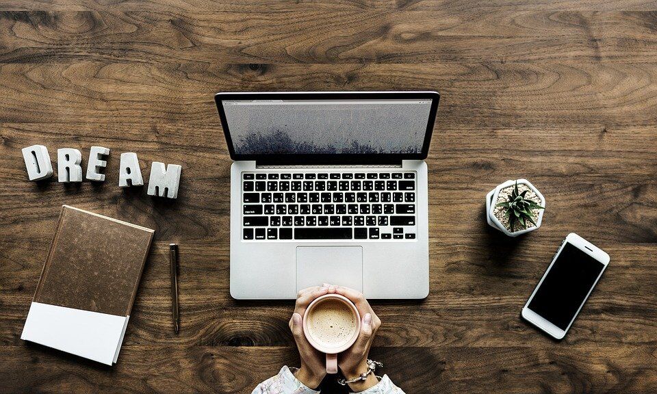 A woman is shown sitting at a work desk, drinking coffee.